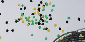 Schwarze, gelbe und grüne Lustballons fliegen über dem Reichstag
