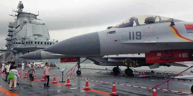 Kampfflugzeuge und Besucher an Deck eines Schiffes