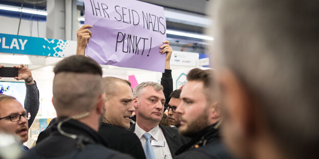 In einer Menschenmenge wird ein Schild hochgehalten, auf dem steht "Ihr seid Nazis, Punkt!"