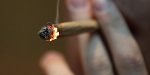 Eine Hand hält einen Joint mit Marihuana