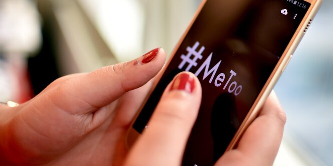 Eine Frau tippt #MeToo ins Handy