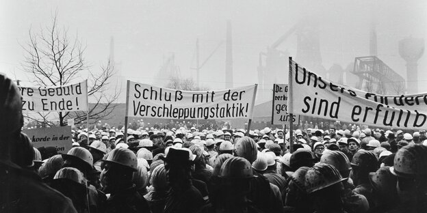 Bergarbeiter demonstrieren mit Plakaten vor einer Zeche