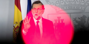 Mariano Rajoy hebt die Hand, ein pinkfarbener Lichtkreis liegt über ihm