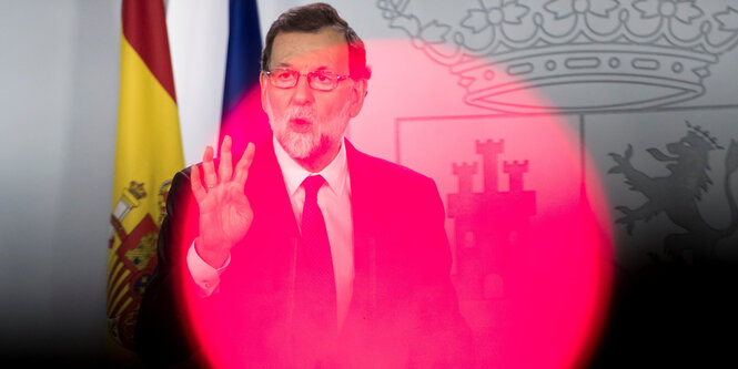 Mariano Rajoy hebt die Hand, ein pinkfarbener Lichtkreis liegt über ihm