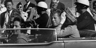 John F. Kennedy sitzt mit seiner Frau Jacqueline und anderen in einem Auto