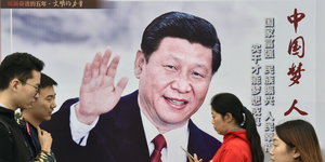 Passanten gehen in Peking an einem Plakat vorbei, das den winkenden chinesischen Präsidenten Xi zeigt