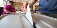 Wahlunterlagen werden in eine Wahlurne gesteckt