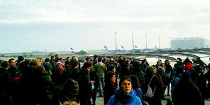 Protestierende stehen am Flughafen in Leipzig/Halle, im Hintergrund Flugzeuge