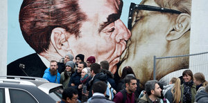 Touristen an einem Rextstück der Berliner Mauer