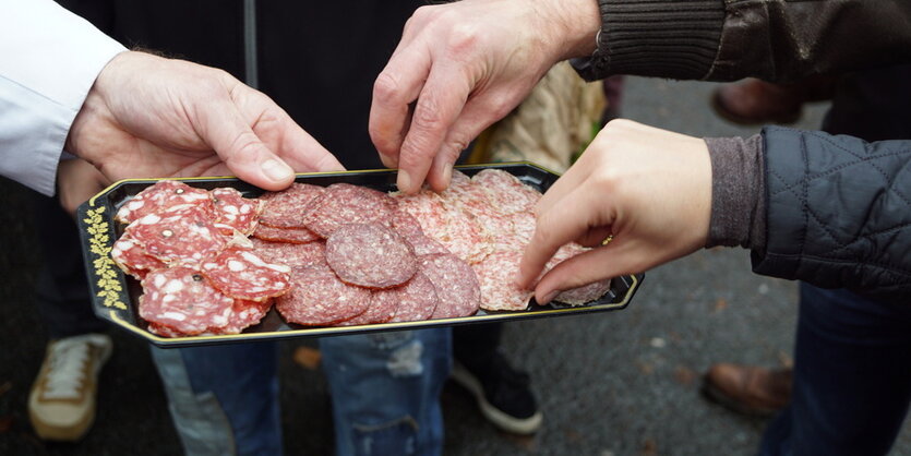 Hände, die zu Wurstscheiben greifen