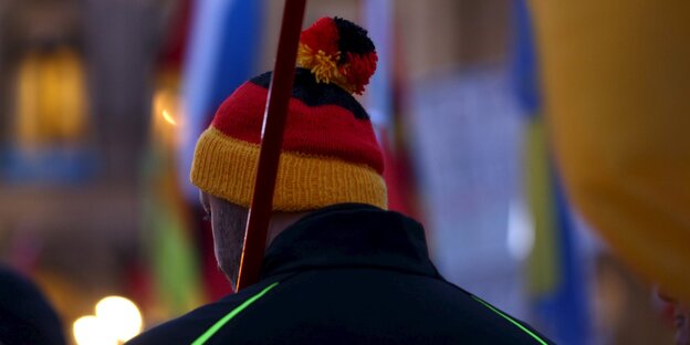 Ein Mann mit Wollmütze in den Farben der deutschen Nationalflagge.