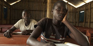 Zwei sudanesische Mädchen sitzen hintereinander an Schultischen