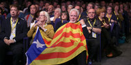 Viele Leute sitzen, zwei sind von einer katalonischen Fahne bedeckt