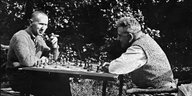 zwei Männer sitzen draußen am Tisch und spielen Schach