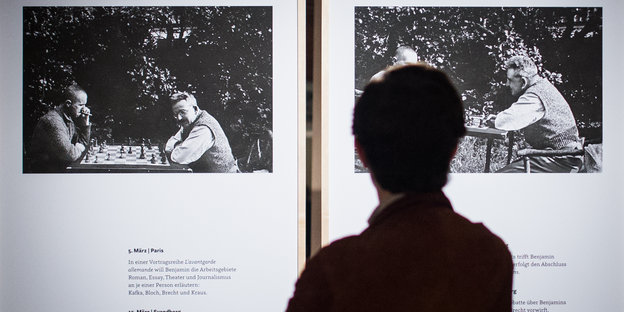 Eine Person sieht sich in der Ausstellung ein Bild an, auf dem Brecht und Benjamin Schach spielem
