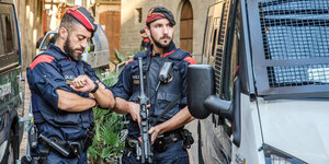 zwei Polizisten zwischen zwei Fahrzeugen