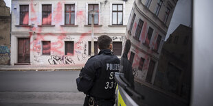 Ein Polizist steht vor einem Haus mit Farbklecksen