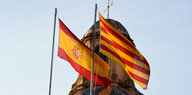 Eine katalanische und eine spanische Flagge flattern vor einer Kuppel im Wind