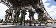 Fünf schwer bewaffnete Soldaten stehen unter dem Eiffelturm