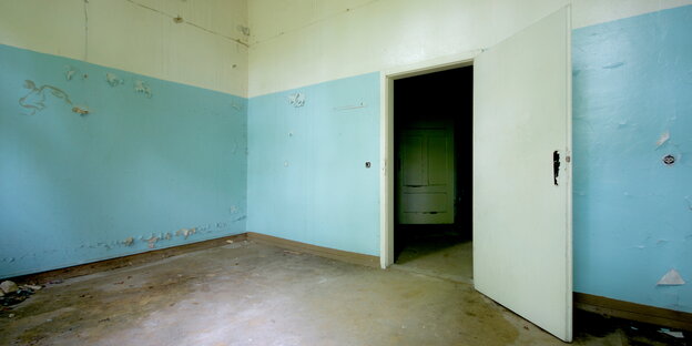 Ein leerer Raum mit offener Tür und blau-weißen Wänden