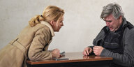 Tatort-Kommissarin Maria Furtwängler lehnt sich über einen Tisch, rechts sitzt ein weinender Mann