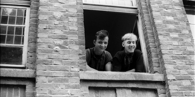 Zwei junge Männer gucken aus einem Fenster