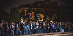 Demonstranten stehen bei Nacht mit Fahnen vor dem katalanischen Parlament in Barcelona