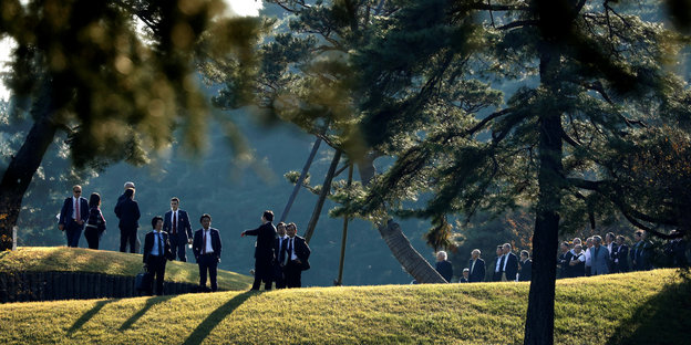 Menschen stehen unter Bäumen auf einem Golfplatz