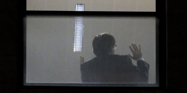 Ein Mann, vermutlich Carles Puigdemont, von hinten: Er sitzt an einem Fenster und gestikuliert