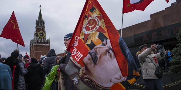 Menschen demonstrieren, einer trägt eine Fahne mit Stalins Konterfei