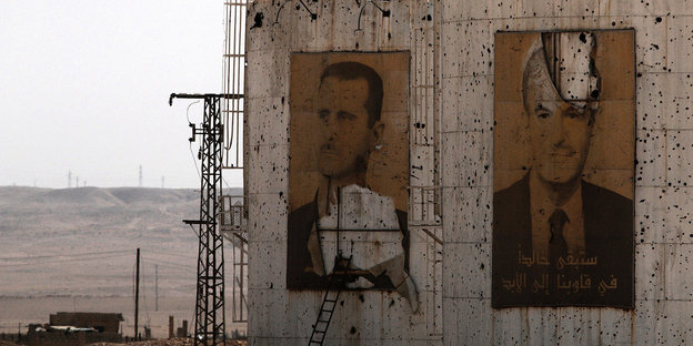Beschädigte Portraits von Baschar al-Assad und seinem Vater hängen an einer beschädigten Wand