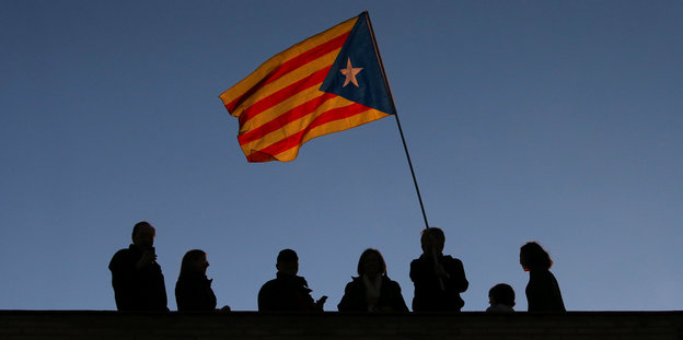 Mehrere Menschen halten ein katalanische Fahne