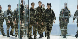 Soldatinnen und Soldaten hinter einer Glaswand