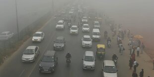 Autos, Mopeds und Rikschas im Smog von Delhi