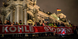Bei Nacht:viele Menschen vor dem Reichstag, die mit einem Transparent gegen den Kohleabbau protestieren