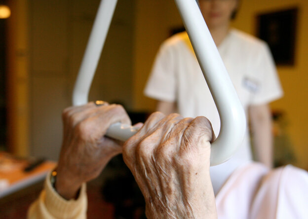 Eine Pflegekraft tritt ans Bett einer Seniorin in einem Pflegeheim.