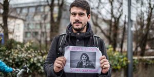 Kerem Schamberger hält ein Plakat in der Hand auf der die Freilassung einer in der Türkei inhaftierten Journalistin gefordert wird