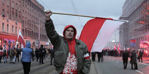 Ein Mann schwenkt eine polnische Flagge auf einer Straße
