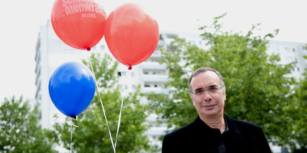 ein Mann und drei Luftballons, ein blauer und zwei rote