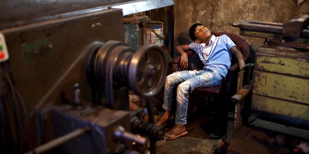 Ein Junge schläft auf einem Sitz in einer Werkstatt