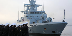 Eine Gruppe Marinesoldaten blickt auf ein weißes Kriegsschiff