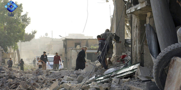 Sechs Menschen klettern über die Trümmer einer zerstörten Straße