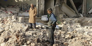 zwei Männer stehen in den Trümmern eines völlig zerstörten Hauses