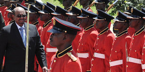 Der sudanesische Präsident geht auf einem roten Teppich in Entebbe, Uganda, an einer Reihe von rotgekleideten Männern der Ehrengarde entlang