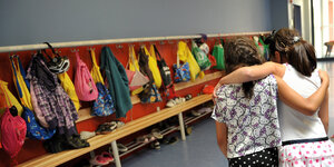 Zwei Schulmädchen gehen Arm in Arm auf eine Garderobe zu
