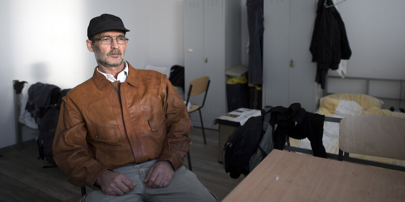 Ein Mann mit Baseballcap und Brille sitzt in einem Zimmer