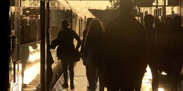Fahrgäste auf einem Bahnsteig - im Gegenlicht der Abendsonne