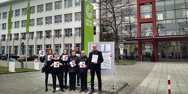 Menschen stehen vorm Goethe-Institut und halten Schilder des GEW hoch