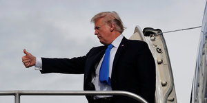 US-Präsident Trump an einer Flugzeugtür, macht eine Daumenhoch-Geste