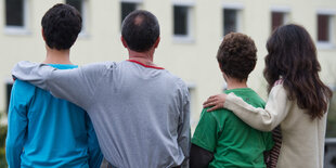 Eine Familie mit zwei Söhnen sitz eng beinander